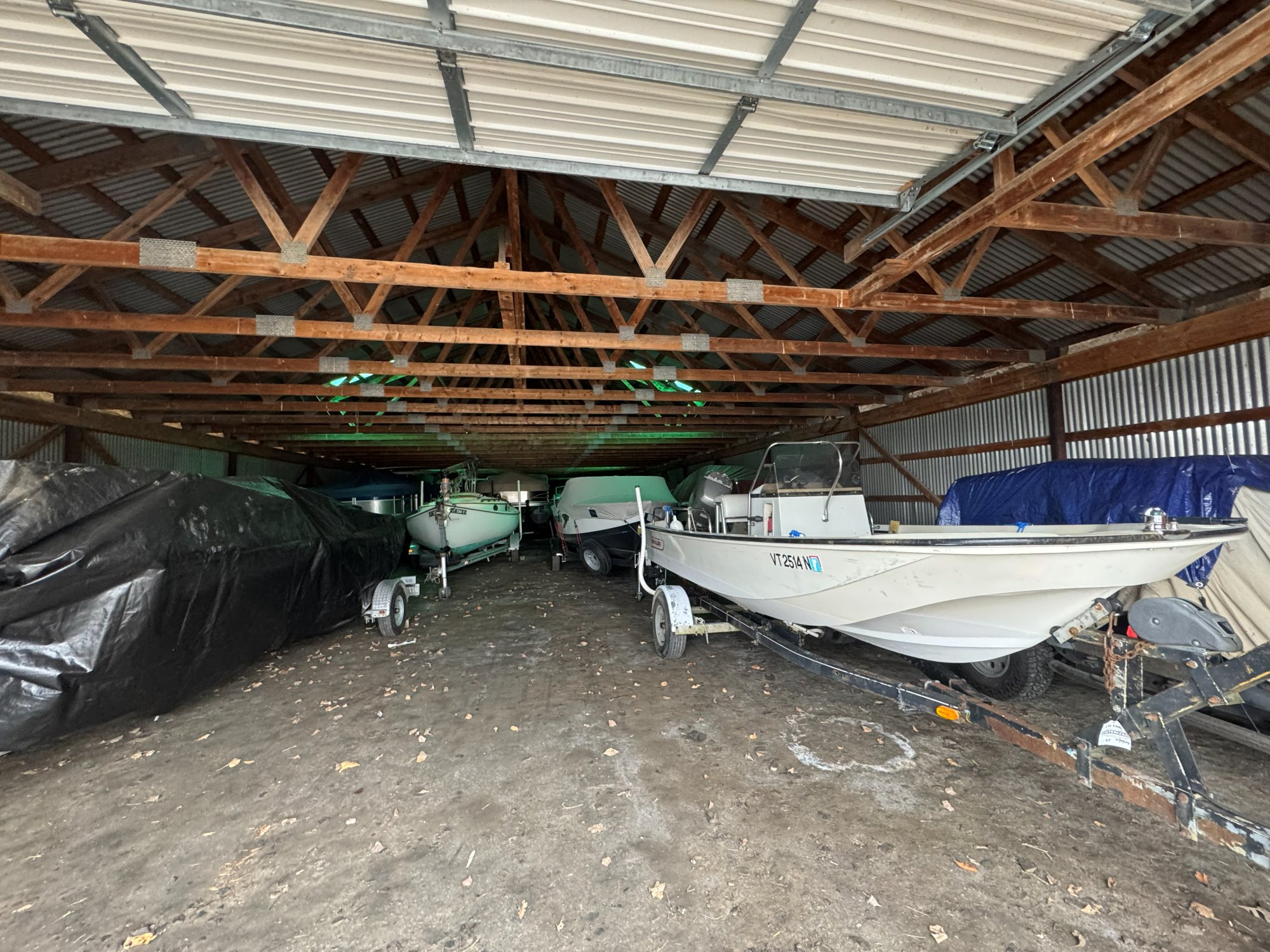 Inside the Island Storage boat barn in North Hero VT — pontoons and runabouts lined up for winter storage under exposed wood trusses